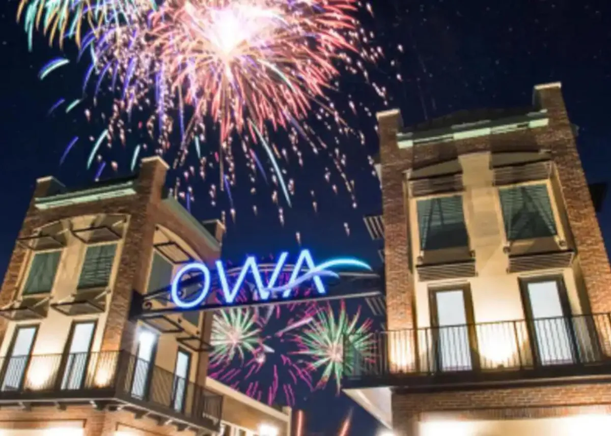 A festive fireworks display lights up the night sky above the OWA sign and building facade, capturing the joy and excitement of visiting this popular amusement and entertainment destination for families.
