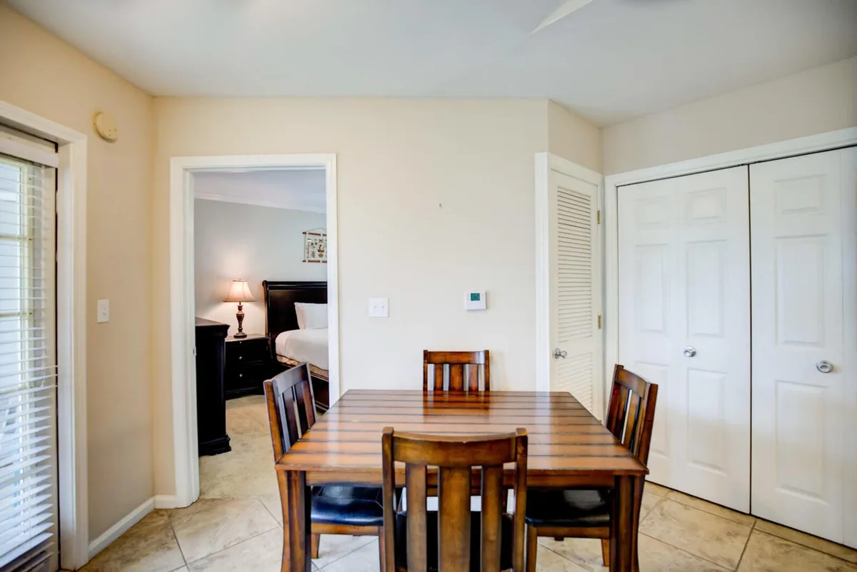 A close-up view of a dining table and chairs set in a cozy nook, with a doorway leading to a bedroom. The intimate setting is perfect for family meals, lively conversation, and game nights.